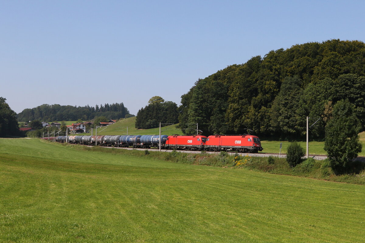 1116 083 und 1116 261 waren am 12. August 2025 mit einem Kesselwagenzug bei Axdorf im Chiemgau in Richtung Salzburg unterwegs.