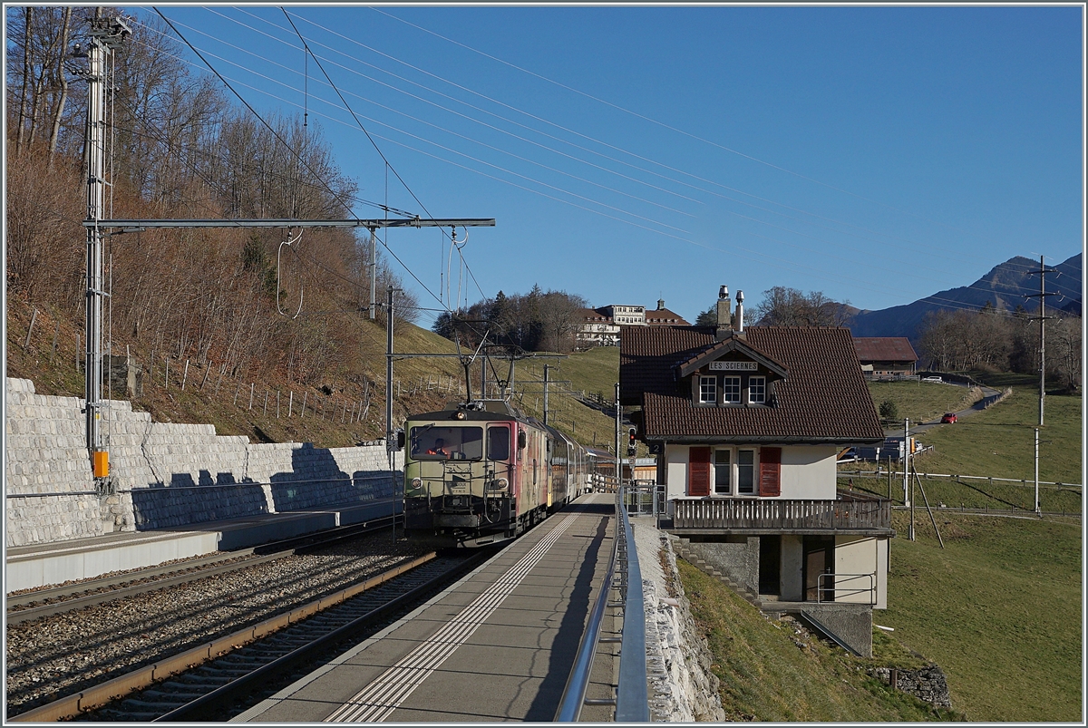 Die MOB GDe 4/4 6006  Aigle les Murailles  ist mit ihrem MOB GoldenPass Panoramic bestehend aus dem Bs 222, Bs 234, Bs 233 und BDs 224 (wobei letztere entgegen der Bezeichnung über 1.Klasse Sitze verfügt) auf dem Weg von Zweisimmen nach Montreux und dabei auf der Durchfahrt in Les Sciernes.

26. Nov. 2020