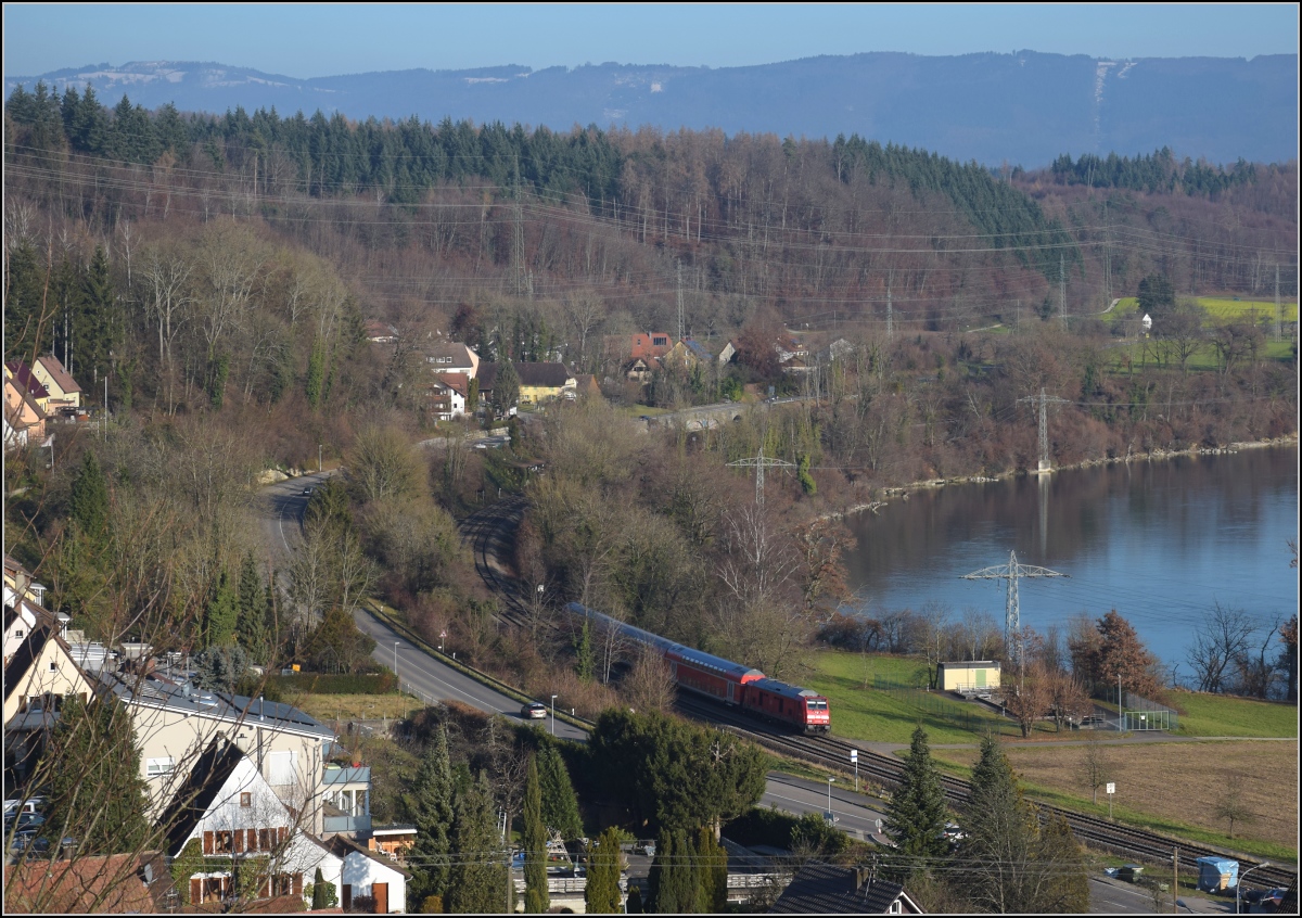 Godot-Express rechts des Hochrheins.

Eine BR 245 mit 3 Dostos. Karsau, Dezember 2021.

An jeder Station wird neuerdings erneut auf Godot gewartet. Er könnte ja noch kommen, auch wenn ihn bis heute niemand gesehen hat. Reisen im 612 war gestern, heute heißt es durch die Landschaft bummeln. Beachtenswert noch: Entgegen der Versprechung leichter und schneller Einstieg fährt hier ein Hocheinstiegsdosto mit. Sehr geschickt bei den besseren Bordsteinen in den Bahnhöfen der Hochrheinbahn. So macht es keinen Unterschied zu den Einstiegszeiten der 612er.