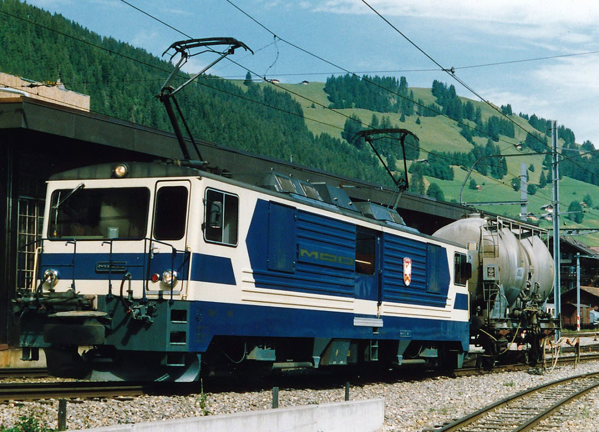 MOB: Während den vielen Jahren, da ich die MOB fotografierte, erlebte ich nie einen eihheitlichen Farbanstrich. Bereits die im Jahre 1983 in den Betrieb gestellten GDe 4/4 6001 bis G004 wurden in einem eher dunkelblauen Farbkleid abgeliefert. Bald aber ist die ursprüngliche einheitliche Farbgebung durch die verschiedesten Werbeaufschriften verdrängt worden. GDe 4/4 6002 im Ablieferungszustand mit einem Rollbockzug in Zweisimmen im Jahre 1984.
Foto: Walter Ruetsch    