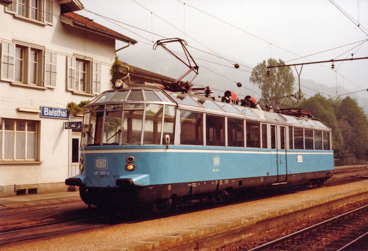 OeBB/DB: An Christi Himmelfahrt feiern die M�nner in Deutschland und Oesterreich den Vatertag. Vor 33 Jahren g�nnten sich deutsche Eisenbahnfreunde zu diesem besondern Anlass mit dem Gl�sernen Zug eine Sonderfahrt nach Balsthal zur Oensingen Balsthal Bahn. Dieser spezielle Zug mit Baujahr 1935 ist im Jahre 1995 bei einem Zugsungl�ck leider derart stark besch�digt worden, dass er im Jahre 1997 ausgemustert werden musste. DB 491 001-4 ex DR ET 9101 vor dem Bahnhof Balsthal an Christi Himmelfahrt im Juni 1982.
Foto: Walter Ruetsch