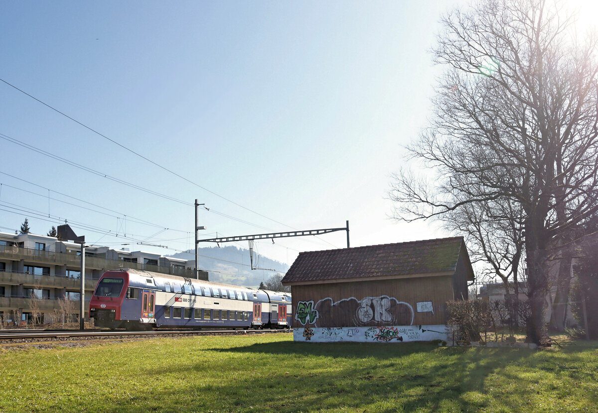 Zürcher S14, Wetzikon - Hinwil: Dies ist der letzte von den SBB betriebene Streckenteil der früheren Strecke Wetzikon-Hinwil-Bäretswil-Bauma. Seit 1969 wird Hinwil-Bauma mit Bussen betrieben; dazu kommt die DVZO Museumsbahn auf dieser Strecke und ein gelegentlicher Güterverkehr bis Bäretswil. Im Bild verlässt ein S-Bahnzug Hinwil Richtung Zürich und weiter, der führende Steuerwagen ist Bt DPZplus 50 85 86-33 013. Im Hintergrund der Bachtel, hoch über Hinwil. 5.März 2025    