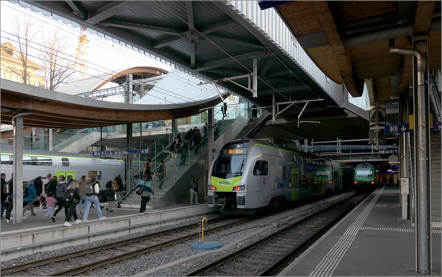Der Bahnhof Bern - 

Im westlichen Bahnhofsbereich wurden 2004 die Bahnsteige verlängert und ein neuer Zugang im Bereich der Schanzenbrücke geschaffen. Da die Bahnsteigdächer wellenförmig über diese neue Zugangsbrücke hinweg geführt sind, wurde dieser Zugang 'Welle' genannt.

Derzeit wird unterhalb der Bahnsteige ein neuer großer viergleisiger Tunnelbahnhof für die RBS gebaut. Damit dafür oben Bahnsteiggleise gesperrt werden können wurde der Bahnsteig an Gleis 9 und 10 auf 785 Meter verlängert um zwei lange Züge hintereinander halten lassen zu können.

Dafür wurde 2019 eine provisorischer Fußgängersteg ähnlich einer Fluggastbrücke mit Anschluss an die Welle gebaut um die Fahrgäste unabhängig vom Bahnsteig einen weiteren Weg zum verlängerten Bahnsteig führen zu können. Dieser Steg ist hier über den Gleisen zu sehen.

07.03.2025

