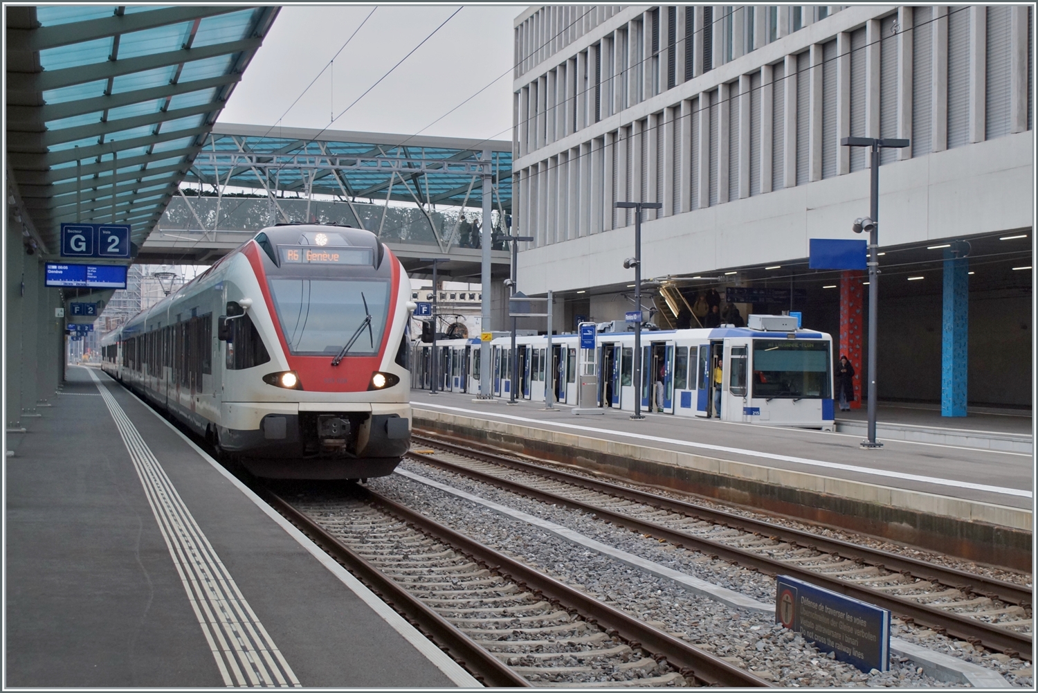Der SBB RABe 523 028 als R6 nach Genève und im Hintergrund zwei TL TSOL Be 4/6 558 Treibwagen als M1 nach Lausanne Flon. 

Renens VD, den 29. Feb. 2024