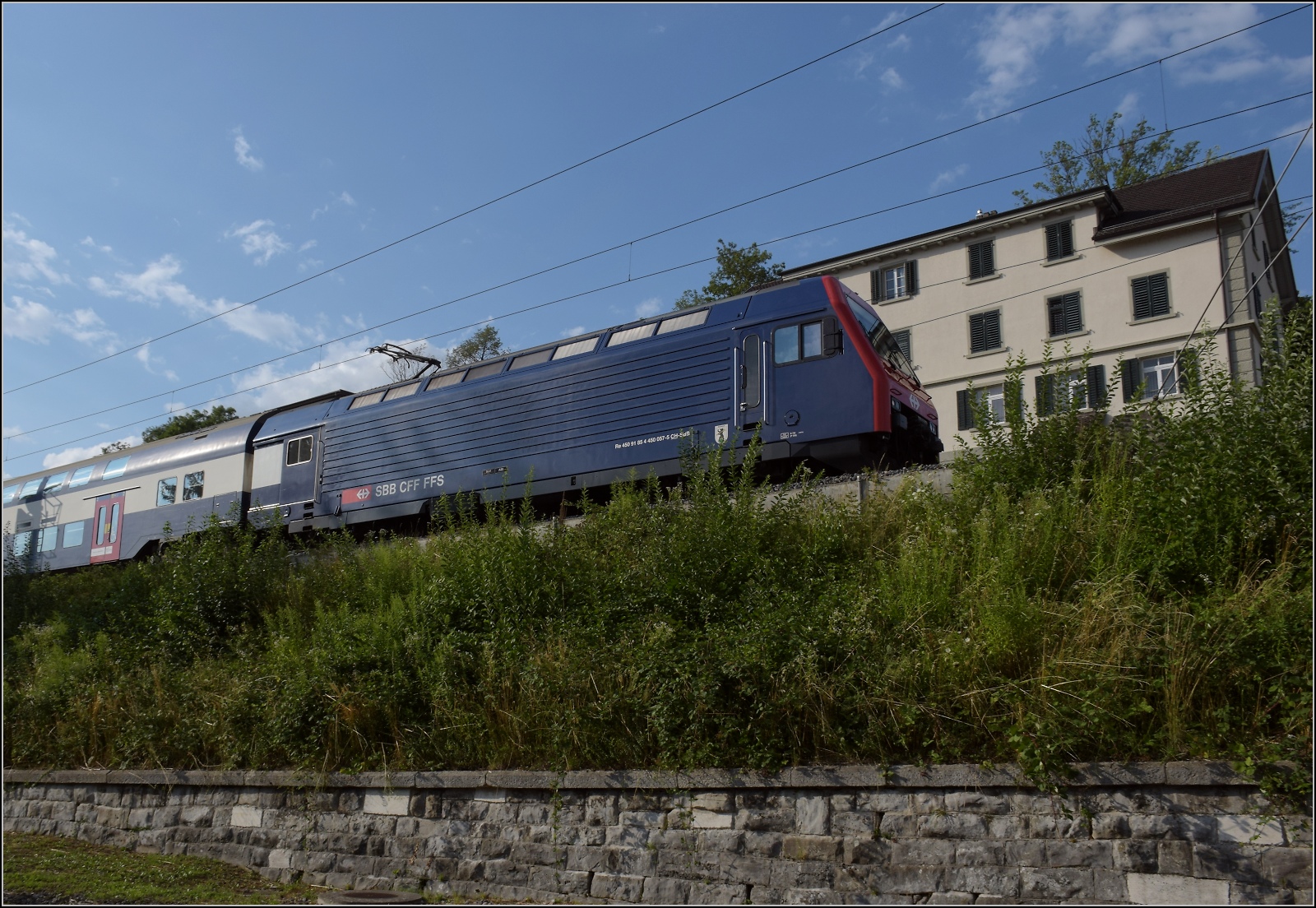 In Uetikon am See f�hrt Re 450 057 mit ihrer S-Bahn vorbei. Juli 2023.