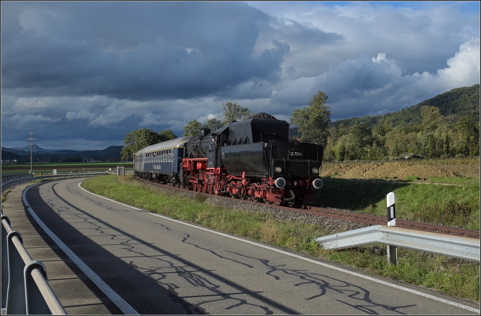Schienenverkehr am Schienerberg. 

52 7596 mit ihrem EFZ-Sonderzug für die SEHR&RS zwischen Ramsen und Hemishofen. Vom Masten leider etwas verdeckt ist der höchste der Hegauvulkane, der Hohenhewen. Oktober 2022.