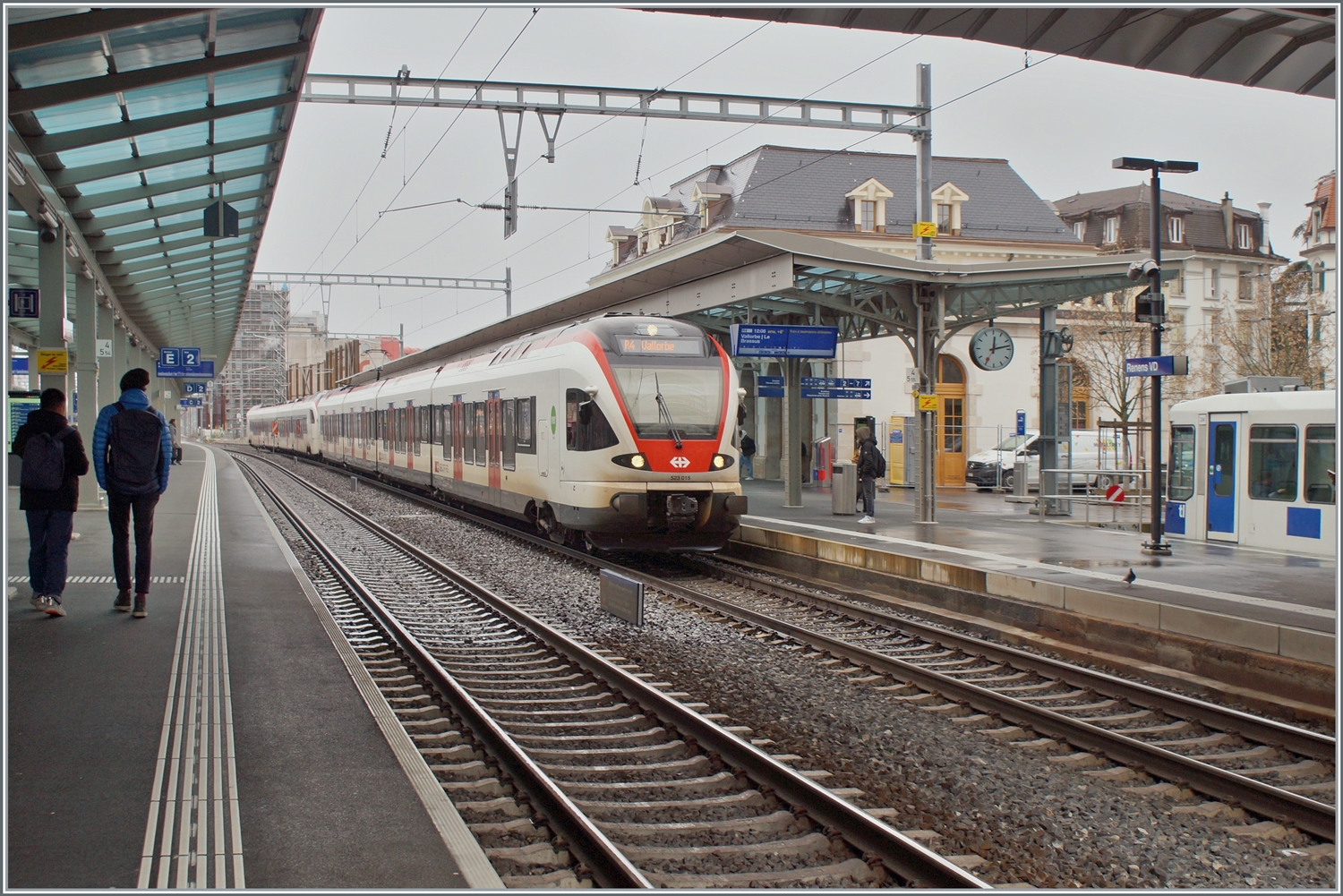 Zwei SBB Flirt, davon je ein RABe 523 und RABe 523.1 verlassen Renens nach Vallorbe und Le Brassus (Flügelzug). Im Hintergrund rechts im Bild ist ein TL TSOL Be 4/6 als m1 zu erkennen. 

14. Dez. 2023 