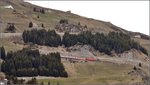 Eine HGe 4/4II mit Regionalzug steigt vom Oberalppass die Kehren am Hang von Nätschen nach Andermatt herab.